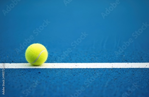 Tennis ball lies on blue court near white line. Play sport match at arena. Tennis equipment, hobby lifestyle, training. Healthy exercise, recreation, sport game.