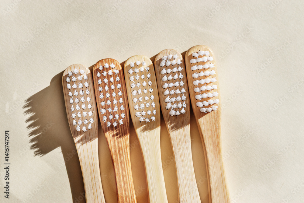 Eco-friendly wood toothbrushes with white bristles at sunlight on beige background. Minimal trend design photo, sustainable hygiene concept, Zero waste lifestyle, eco-conscious living, dark shadow