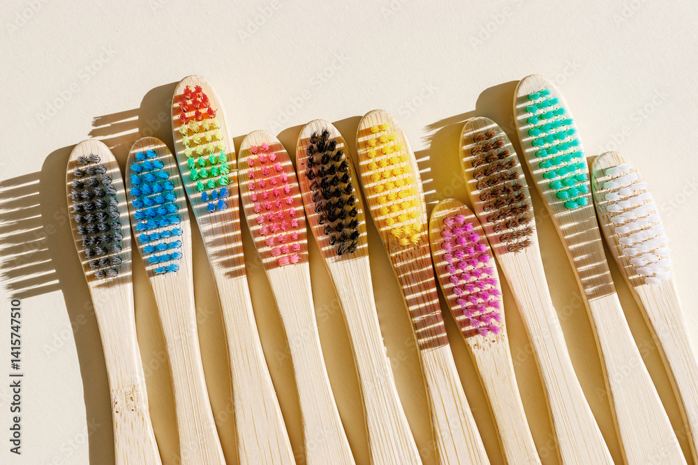 Eco-friendly wood toothbrushes with soft colorful bristles at sunlight on beige background. Minimal design photo, sustainable hygiene concept, Zero waste lifestyle, eco-conscious living, hard shadow