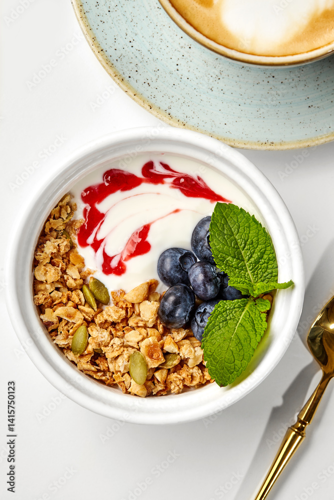 Healthy breakfast with yogurt, granola, berries and cappuccino enjoyed from above