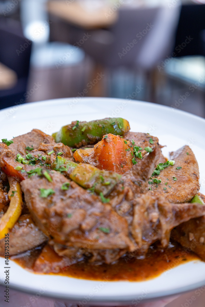 A plate of meat with Potato and herbs