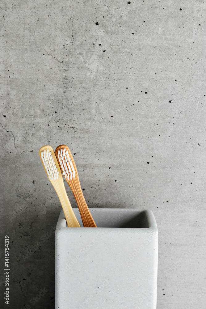 Eco-friendly wood toothbrushes with soft white bristles in modern grey concrete holder. Minimal bathroom design, sustainable hygiene concept, Neutral tones, zerowaste lifestyle, eco-conscious living