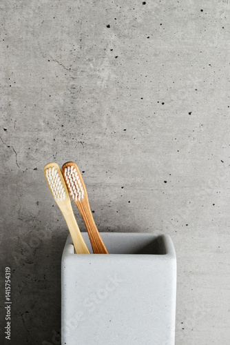 Obraz na płótnie Eco-friendly wood toothbrushes with soft white bristles in modern grey concrete holder. Minimal bathroom design, sustainable hygiene concept, Neutral tones, zerowaste lifestyle, eco-conscious living w salonie