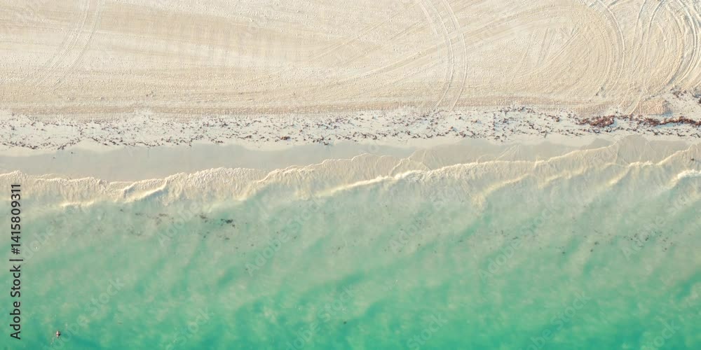 Hermosa toma aérea cenital de una playa con arena blanca, agua azul turquesa, vista superior de una playa paradisíaca con un drone