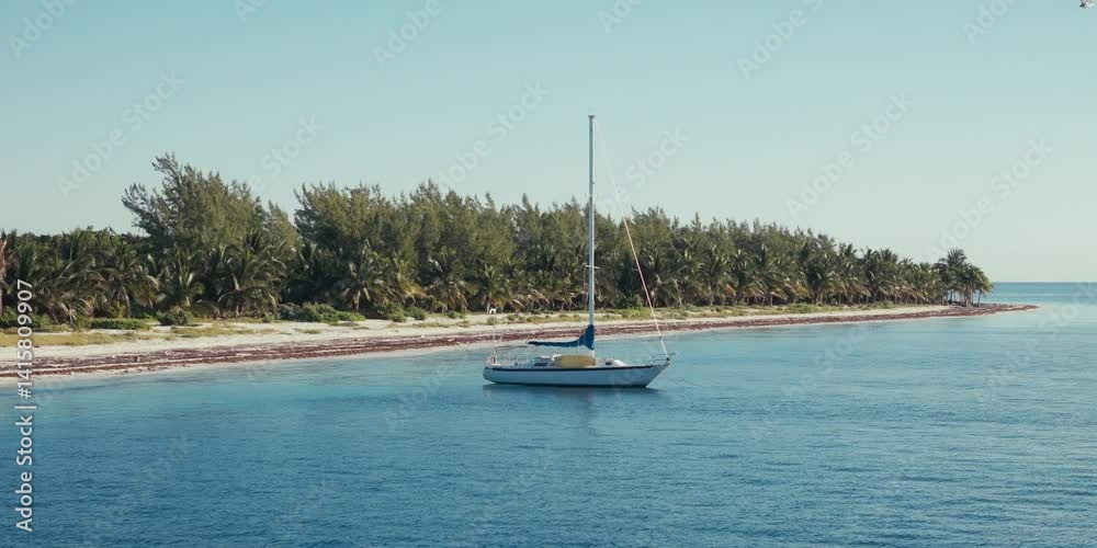 toma aérea orbital con drone de un velero a la orilla de la hermosa playa con aguas azul turquesa del Caribe, en la Riviera Maya México