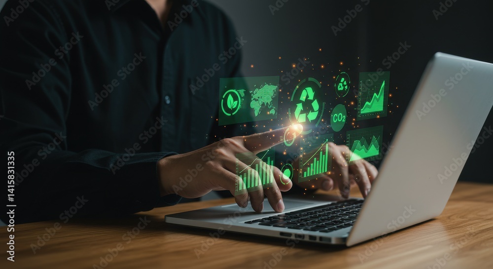 Person using laptop with green technology interface on wooden desk in dark environment showing sustainability