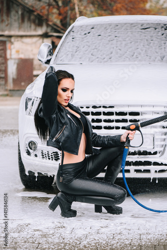 Sexy woman washing car in leather outfit