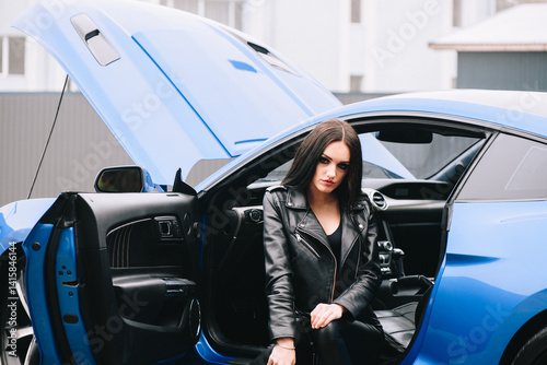 Stylish woman sitting in sports car with open door