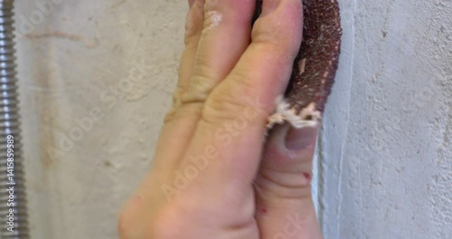 Metal pipe restoration happening through careful sanding process, removing peeling paint layer with professional manual technique and sandpaper precision, revealing smooth underlying surface