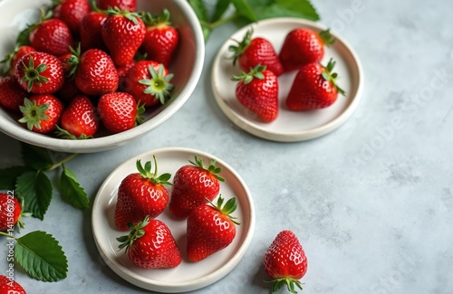 Fresh ripe strawberries, collected from garden, presented on white plates and bowl. Homemade winter fruit blanks, berry harvest. Sweet red fruits, healthy vegan snacks, jams or desserts preparations.