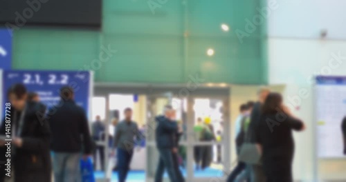 Anonymous attendees are walking in a busy convention center, their faces blurred to maintain anonymity, creating a sense of bustling activity and the scale of the event