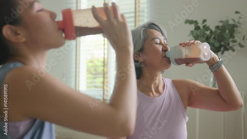 Young adult child active mature middle age old mum drink whey protein shake bottle diet food after home workout. Love health care older aged mom asia elder people happy relax sport protect aging life.