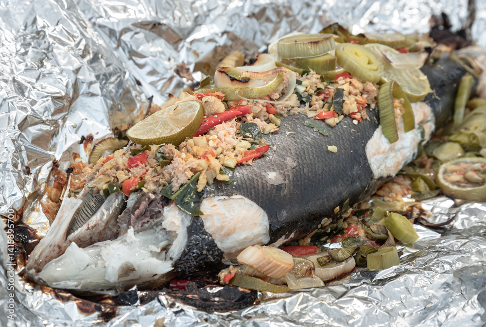 Baked Whole Salmon with Herbs in an Oven, ingredient include Coriander root, Ginger, Galangal, Kaffir lime, Leek, chopped together and Bird's eye chili with Slice lemons place on the Salmon fish.