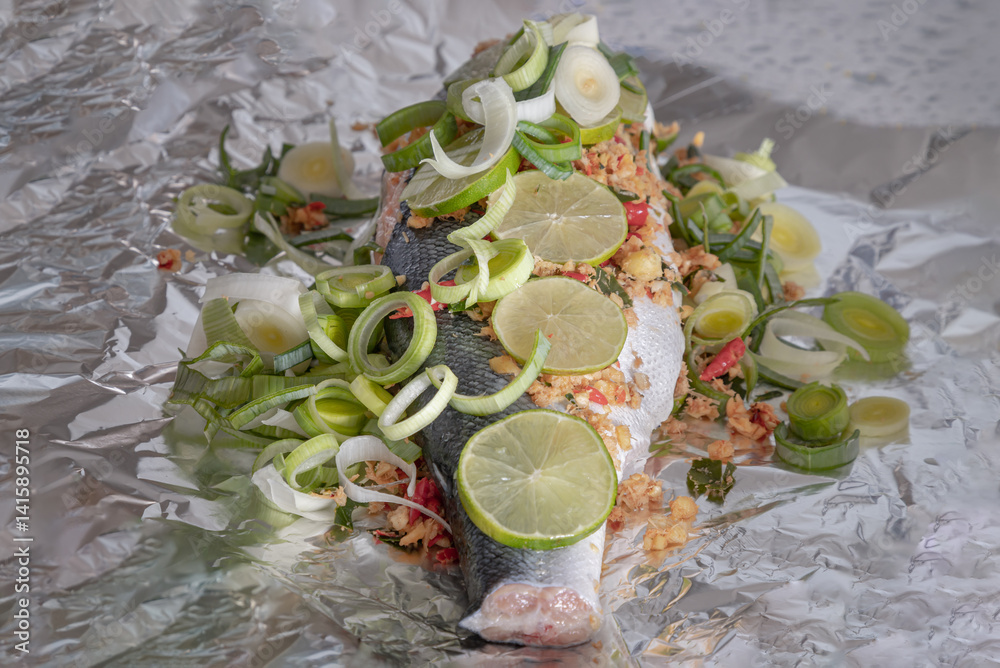 Prepare Whole Baked Salmon with Herbs on aluminium foil. ingredient include Coriander root, Ginger, Galangal, Kaffir lime, Leek, chopped together and Bird's eye chili with Slice lemons place on fish.