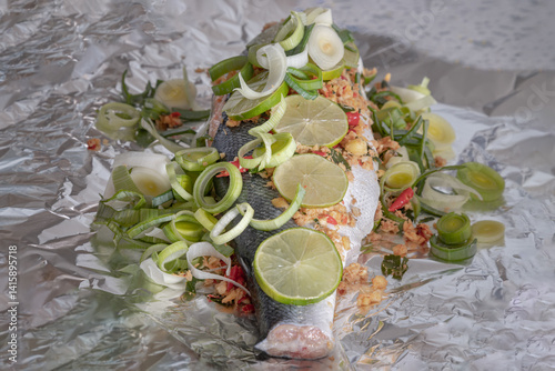 Obraz na płótnie Prepare Whole Baked Salmon with Herbs on aluminium foil. ingredient include Coriander root, Ginger, Galangal, Kaffir lime, Leek, chopped together and Bird's eye chili with Slice lemons place on fish. w salonie