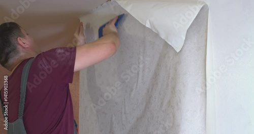 A person who covers the walls with new wallpaper, smoothing them on the wall with a special spatula.