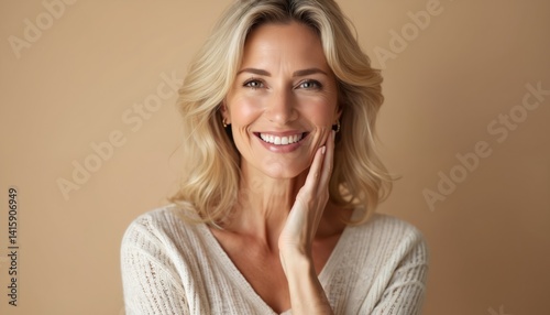 Beautiful middle-aged woman with blond hair smiles. Attractive caucasian female face close-up. Happy, healthy woman in 40s on beige background. Confident woman shows natural beauty, fresh face.