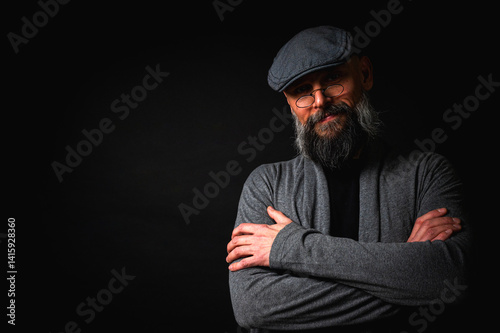 Obraz na płótnie emotional, macro portrait of a serious bearded man in a cap and glasses on a black background. Stylish, intense look with a confident and mysterious expression, emotions place for inscription on a bil w salonie