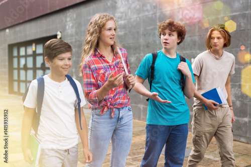 Group of four teens going from school together and talking.