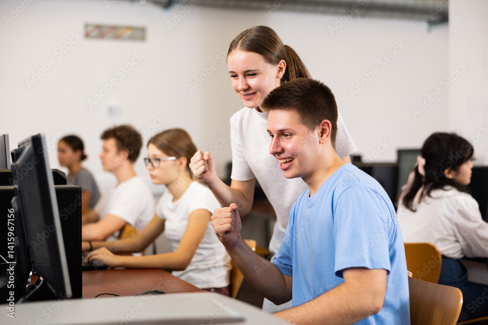 Teenager girl helps friend solve problem on computer in a school class Teenager girl helps friend solve problem on computer in a school class