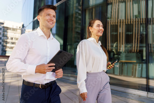 Colleagues Enjoying a Productive Afternoon Walk Outside a Modern Office in a Vibrant Urban Setting photo