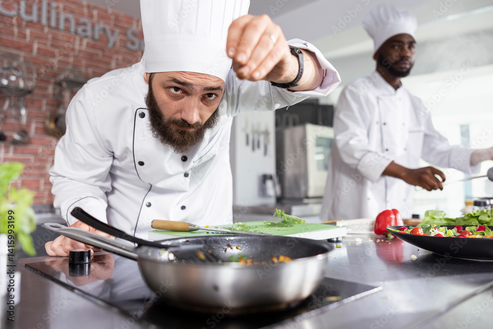Culinary expert in commercial kitchen prepares a dish with fresh basil and parsley, showcasing gastronomy expertise in fine dining and food prep. Young man chef sprinkles rosemary leaves. Culinary expert in commercial kitchen prepares a dish with fresh basil and parsley, showcasing gastronomy expertise in fine dining and food prep. Young man chef sprinkles rosemary leaves.
