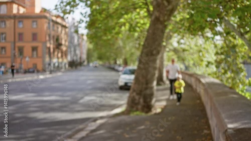 Wallpaper Mural Defocused view of man and child walking along sunny street in rome italy with trees and historic buildings in the background. Torontodigital.ca
