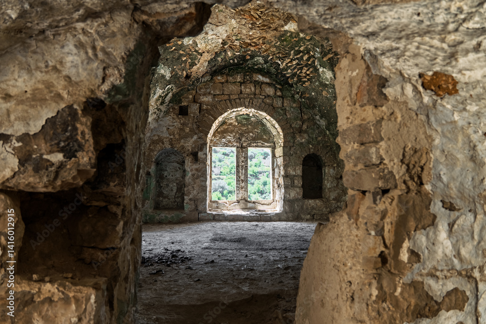 Fototapeta premium Abandoned stone structure with arched windows, weathered walls, and scenic forest landscape visible through the opening, historic mysterious atmosphere. Lifta, Israel