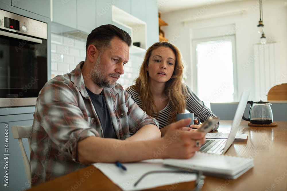Fototapeta premium Close up of a couple going over home finances in the kitchen in the morning