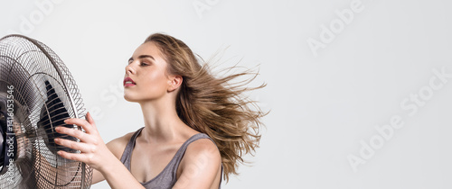 Woman enjoying cool air from fan on hot summer day with copy space
