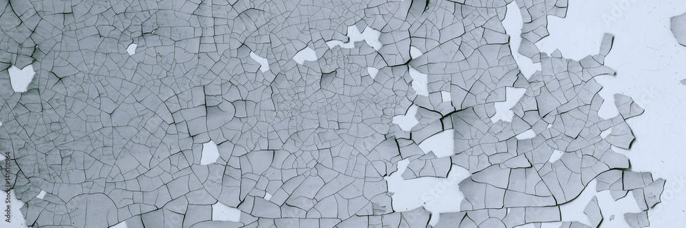 Peeling paint on the wall. Panorama of a concrete wall with old cracked flaking paint. Weathered rough painted surface with patterns of cracks and peeling. Panoramic texture for background and design.
