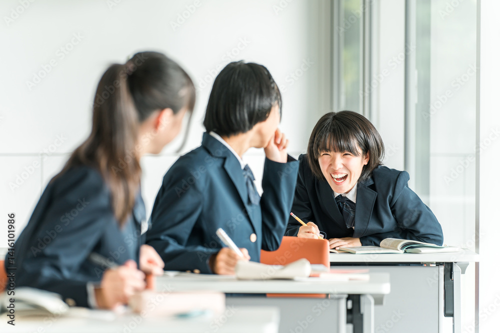 Fototapeta premium 学校で授業中に後ろの席の生徒と話す小学生・中学生・高校生・女子高生（友達） 