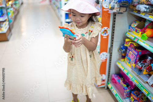 Obraz na płótnie Little girl enjoy shopping toy on shelf in supermarket w salonie