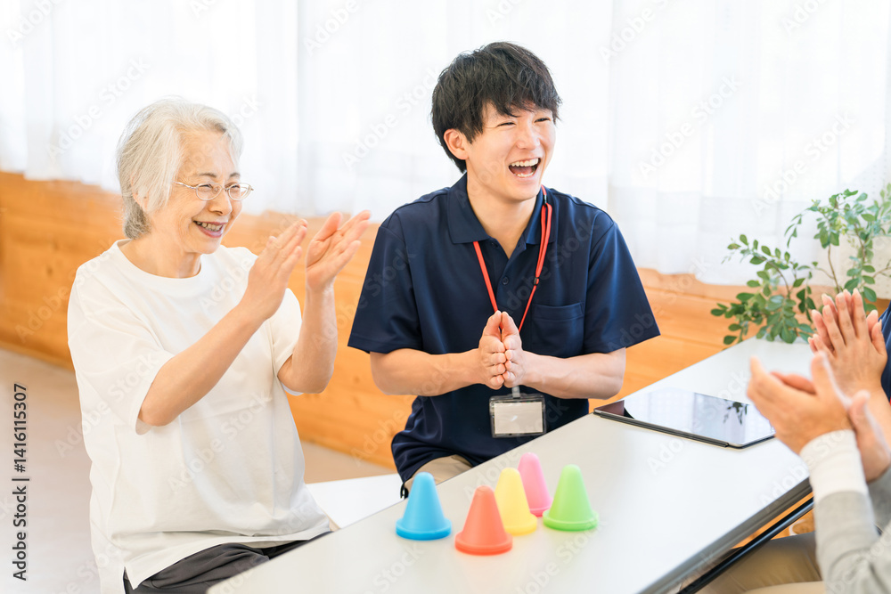 Obraz premium リハビリ施設,介護施設で働く若いアジア人男性スタッフとシニア女性