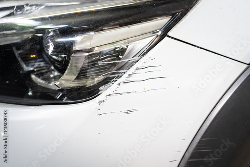Small scratch on car front bumper close up. Claim and insurance concept. Car with scratched bumper paint and dented parts on the side.