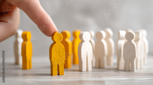 A Finger Selecting a Bright Yellow Wooden Figure from a Group of White Ones, Representing Choice, Individuality, and Recruitment.