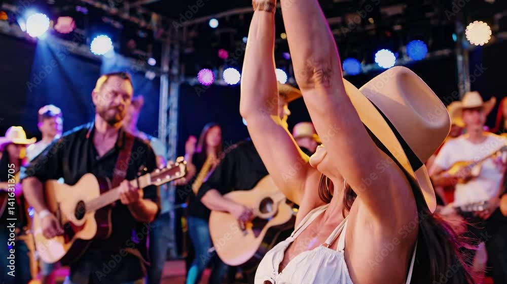Vibrant country music video scene with a joyful woman in a cowboy hat, captured from a low-angle, surrounded by musicians and colorful stage lights.