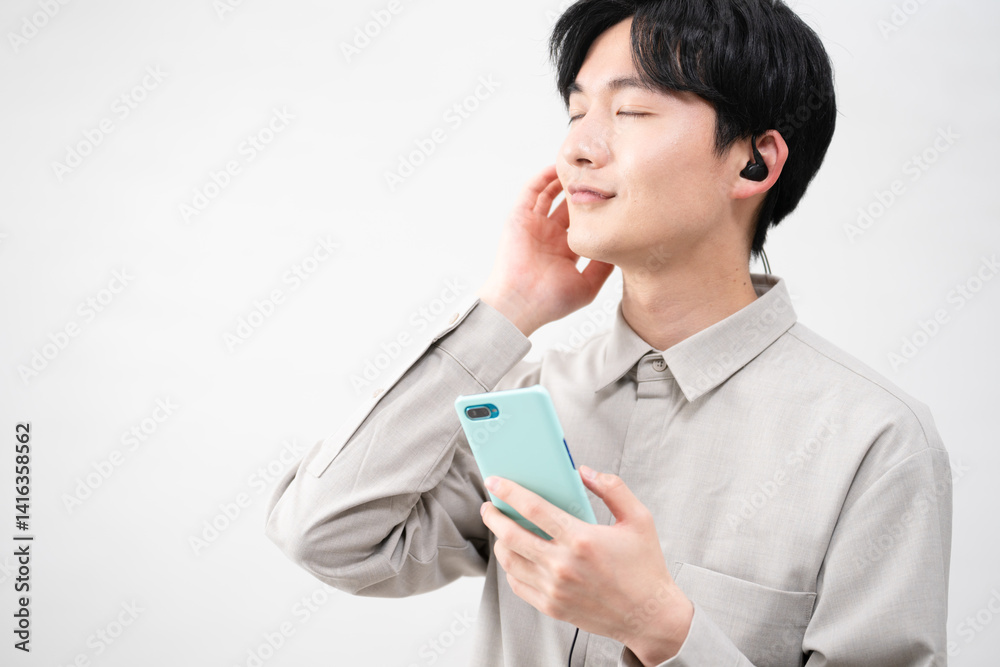 有線イヤホンで音楽を聴く若い男性