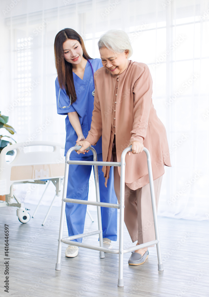 Asian doctor or caregiver helping assistance old woman to standing with walker in hospital, Young nurse supporting senior patient walk slowly frame nursing home care, Healthy wellness being concept.