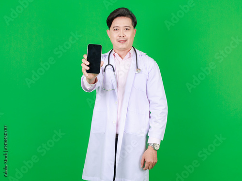 Portrait of asian middle aged confident man doctor in white coat with stethoscope standing holding using smartphone looking at camera on green background, Consultation healthcare professional concept.