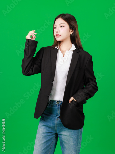 Portrait of asian beautiful young woman long hair, confident charming wearing white shirt black suit and blue jean posing looking at camera in green background studio. Fashion lifestyle concept.