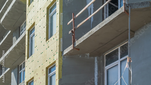 Construction work on the exterior cladding of the building. Laying of thermal insulation material on the walls. Insulation of the house. Plastering the walls. Balconies of a house under construction.