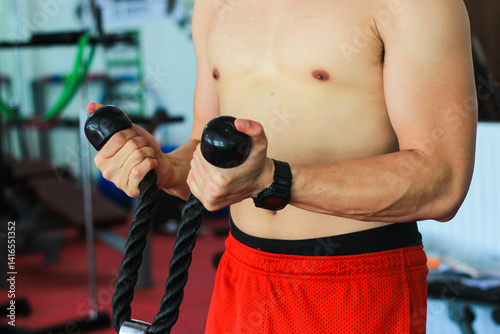 Young man doing exercise by pulling rope photo