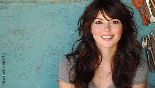 Smiling young woman with brown hair against teal wall.