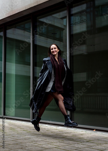 Gen Z woman running and jumping in front of an office building in Stuttgart, Germany