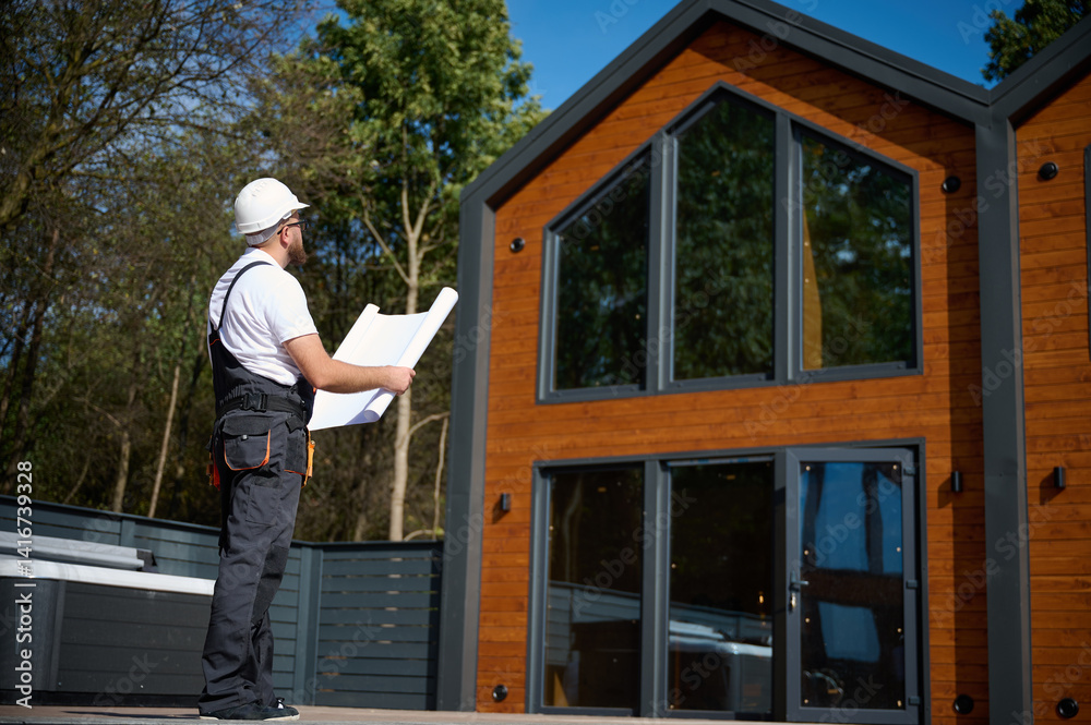 custom made wallpaper toronto digitalArchitect hold plan. Bearded architect wearing hardhat holding project blueprints paper plans standing near comlex of new modern houses looking to something at construction site.