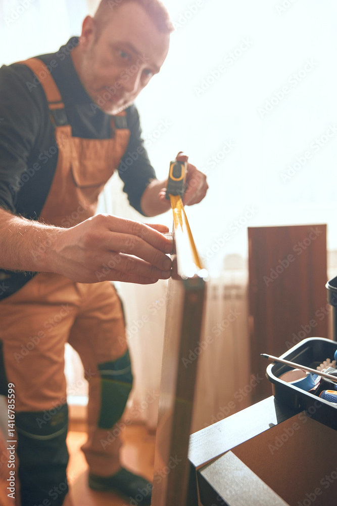 Carpenter working and assembling furniture in a new apartment.