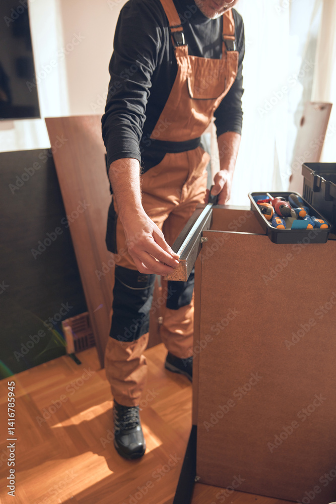 Carpenter working and assembling furniture in a new apartment.