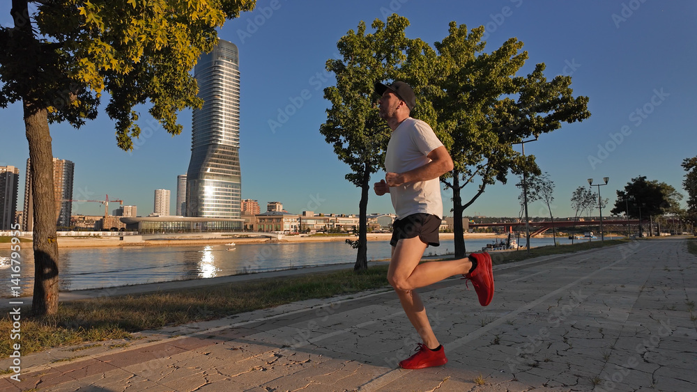 Man exercising and jogging in a park during summertime golden hour time.