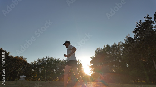Obraz na płótnie Man exercising and jogging in a park during summertime golden hour time. w salonie